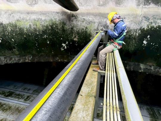 Technician measuring a cooling tower component during the site inspection