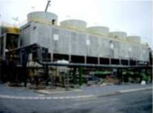 A new concrete cooling tower with five fan stacks beside a plant road