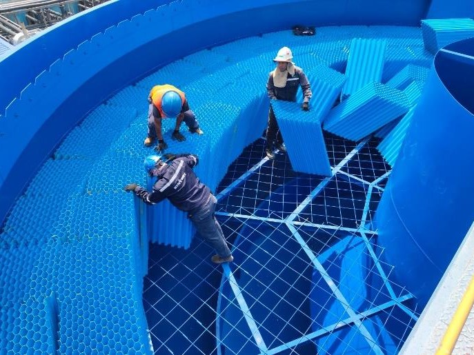 Technicians installing blue tube-settler modules inside a clarifier tank
